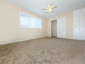 Pico Rivera apartment for rent - A room with a carpeted floor, a ceiling fan, and a door leading to another room.
