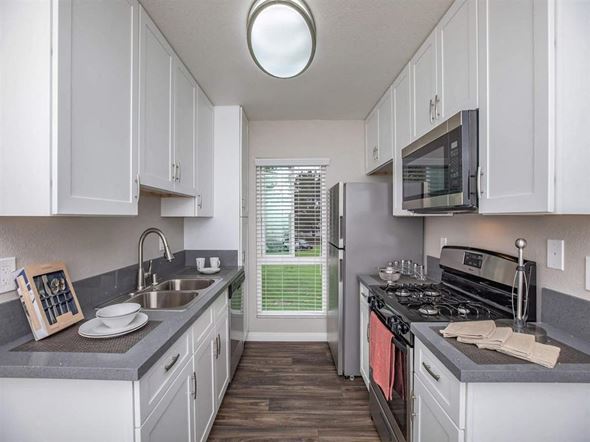 Santa Ana apartment for rent - A kitchen with white cabinets and a black stove top oven.