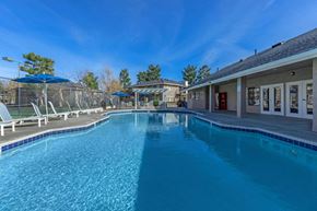 Victorville apartment for rent - A large swimming pool with a blue tiled edge and a building in the background.