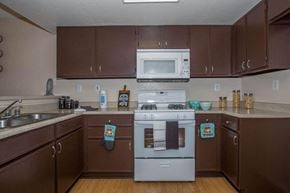 Victorville apartment for rent - A kitchen with brown cabinets and a white stove top oven.