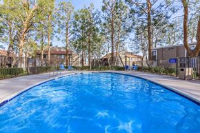 Barstow apartment for rent - A large blue swimming pool surrounded by trees.