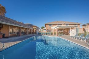 Victorville apartment for rent - A swimming pool in front of a building with a clear blue sky.