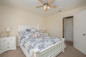 Victorville apartment for rent - A bedroom with a bed, dresser, and ceiling fan.