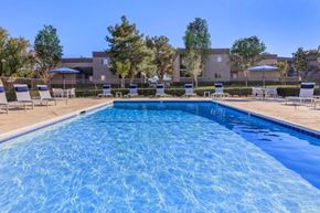 Hesperia apartment for rent - A swimming pool surrounded by lounge chairs and trees.