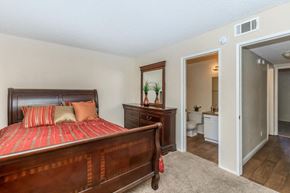 Hesperia apartment for rent - A bedroom with a large bed and a dresser with a mirror.