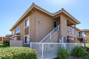 Vista apartment for rent - A two-story house with a white fence in front.