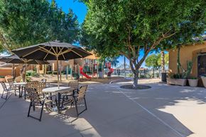 Phoenix apartment for rent - a patio with tables and chairs and trees and a playground