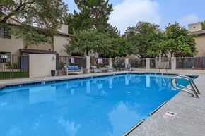 Phoenix apartment for rent - a large blue pool in front of a building with trees
