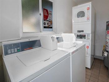 Chestnut and hedding laundry room with two washing machines and two dryers