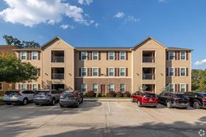 Bentonville apartment for rent - A sunny day at a large apartment complex with cars parked in the lot.