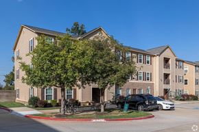 Bentonville apartment for rent - A large apartment complex with a parking lot in front.