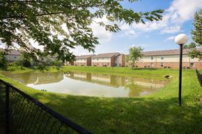 La Porte apartment for rent - Pond in the middle of a grassy area with apartment buildings in the background at Maple Tree Apartments in LaPorte, IN