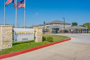 Houston apartment for rent - The entrance to Summerdale Apartments is marked by a large sign and flags.