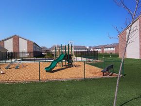 La Porte apartment for rent - Playground with a slide and monkey bars inside a fenced area at Maple Tree Apartments in LaPorte, IN