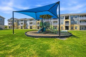San Antonio apartment for rent - A playground with a blue canopy and a green slide is surrounded by apartment buildings.