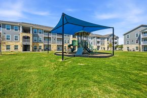 San Antonio apartment for rent - A playground with a blue canopy and a green slide is in front of apartment buildings.