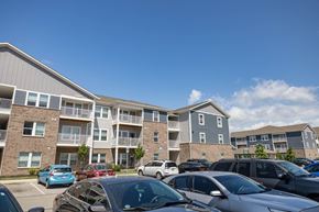 Whitestown apartment for rent - A parking lot with cars and apartment buildings in the background.