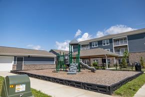 Whitestown apartment for rent - A playground with a green slide and a sandbox in front of a building.