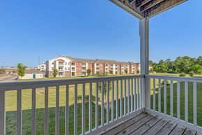 Houston apartment for rent - A view from a balcony overlooking a grassy area and apartment buildings.