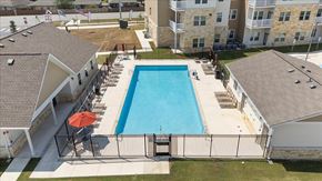 San Marcos apartment for rent - A swimming pool surrounded by a fence and a building in the background.