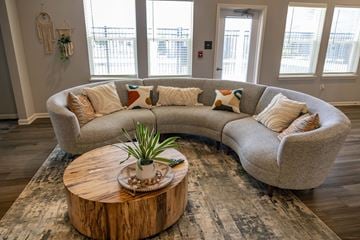 Whitestown apartment for rent - A living room with a large couch and a coffee table with a plant on it.