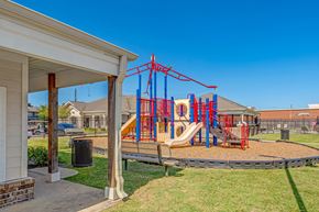 Houston apartment for rent - A playground with a red and blue swing set.
