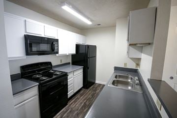 Batesville apartment for rent - A kitchen with black appliances and white cabinets.