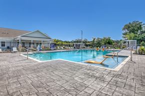 Palm Bay apartment for rent - A large outdoor swimming pool with a sun lounger and a building in the background.