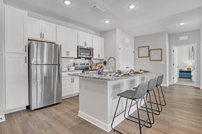 Palm Bay apartment for rent - A kitchen with a refrigerator, microwave, and a counter with chairs.