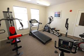 Kalamazoo apartment for rent - Fitness center with cardio equipment and a weight machine at Canterbury Apartments in Kalamazoo, Mi