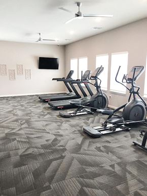 New Albany apartment for rent - A fitness center with treadmills and a television on the wall.
