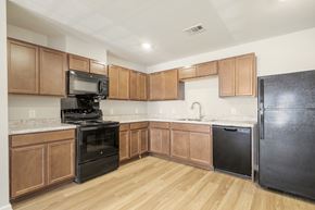Del Valle apartment for rent - A kitchen with wooden cabinets and black appliances.