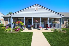 Frankfort apartment for rent - the front of Frankfort Place apartments clubhouse with flowers on the porch