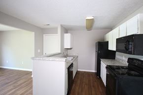 Tipton apartment for rent - a kitchen with white cabinets and black appliances