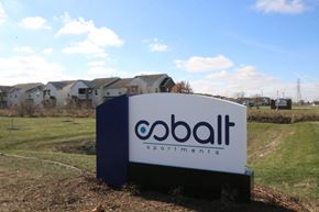 Kokomo apartment for rent - A Cobalt Apartments sign is in front of a grassy area with houses in the background.
