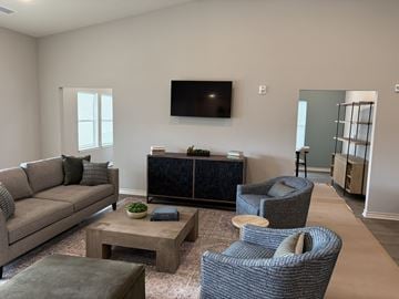 Kansas City apartment for rent - A living room with a grey sofa, a coffee table, and a television mounted on the wall.