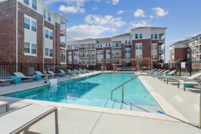 Slidell apartment for rent - pool with lounge chairs with apartment buildings at The loft apartments in Slidell, LA