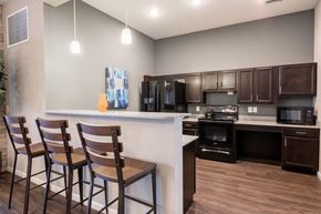 Avon apartment for rent - Clubhouse kitchen with 3 barstools and cabinets and black appliances at Mosaic Apartments in Avon, Indiana