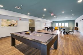 Indianapolis apartment for rent - a pool table with tables and chairs in the background at The Vue apartments in Indianapolis