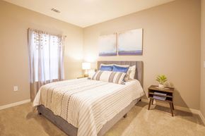 Melbourne apartment for rent - Apartment bedroom with a bed, nightstand and two pictures at Trillium apartments in Melbourne fl
