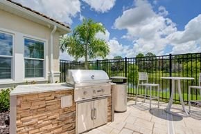 North Port apartment for rent - Grill and table with chairs and a pond in the background at flats at sundown luxury apartments in north port florida