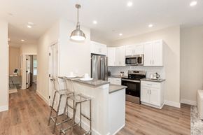 West Babylon apartment for rent - A modern kitchen with white cabinets and a wooden floor.