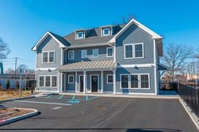 Lindenhurst apartment for rent - A large two-story house with a grey and white exterior and a black roof.