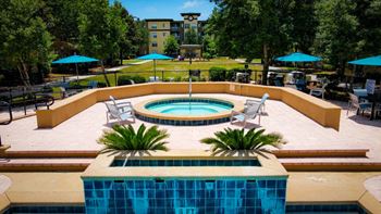 A pool surrounded by a patio and trees.