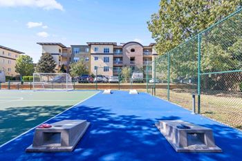 A blue trampoline with two grey safety bars in the foreground and apartment buildings in the background.