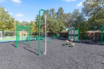 A playground with a green swing set and a basketball hoop.