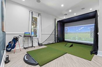 A room with a golf simulator and a golf bag.