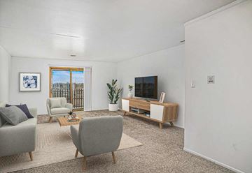 Merrillville apartment for rent - A living room with a grey sofa, a grey armchair, a wooden cabinet, a rug, and a painting on the wall.