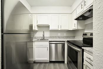 A kitchen with refrigerator and white cabinets
