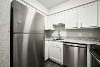 A kitchen with white cabinets and a stainless steel refrigerator